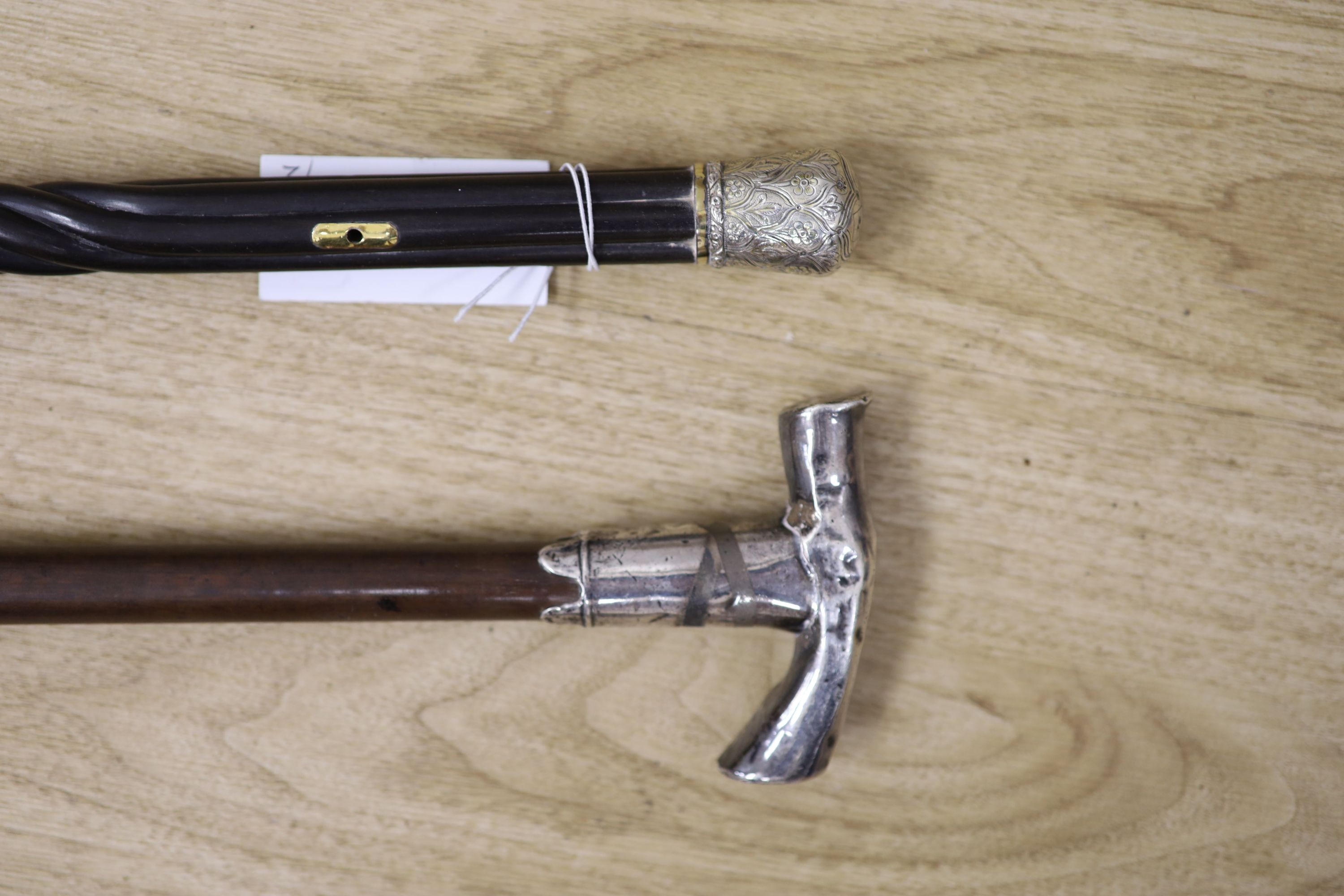 A 19th century Ceylonese ebony and silver topped walking stick and a white metal handled walking stick